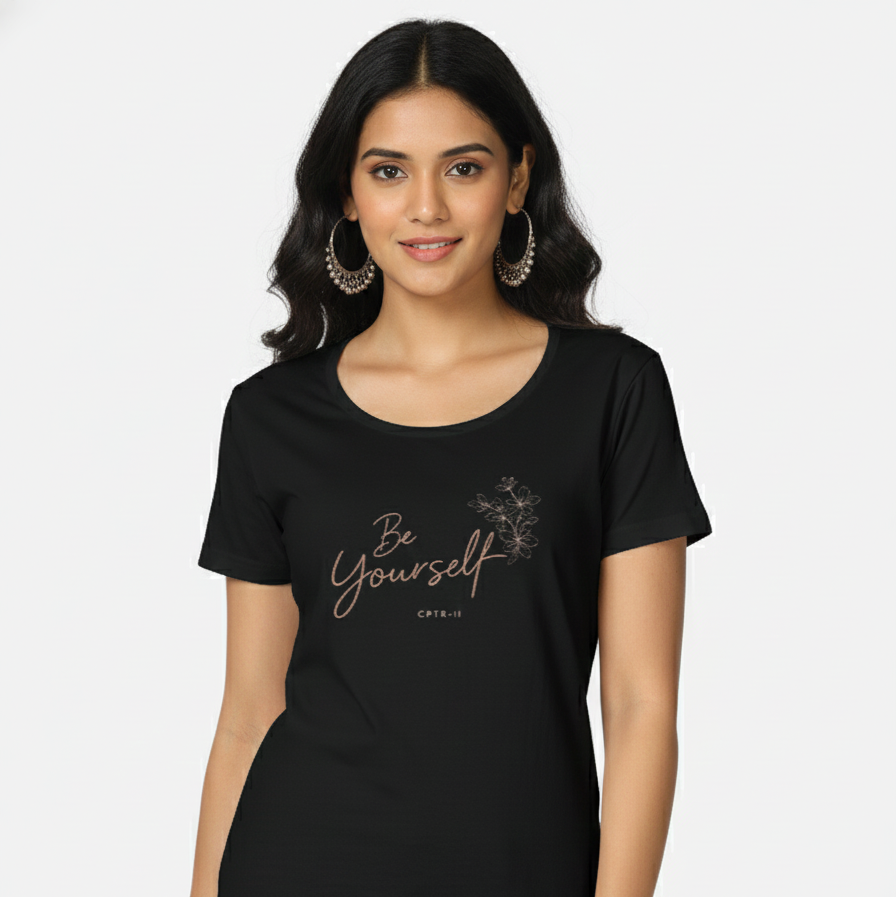 Woman wearing a black t-shirt with 'Be Yourself' text on a white background - View 1