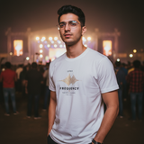 Man wearing a white t-shirt with text Frequency Music Edition T-shirt and graphics at a concert or event. - View 2